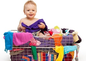 Happy smiling toddler in big basket with clothes